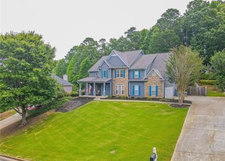 a view of a house with a big yard and large trees