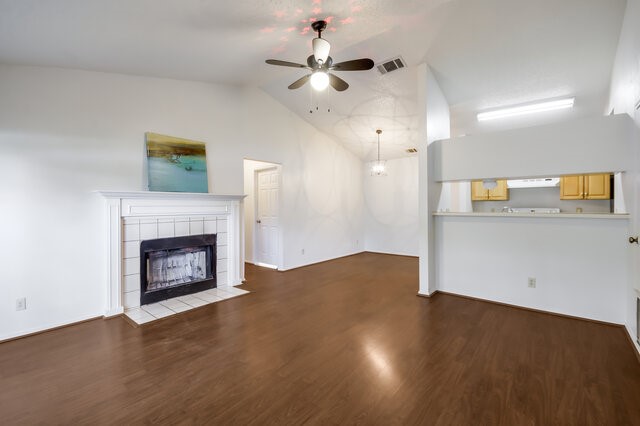 an empty room with wooden floor a fireplace and a ceiling fan