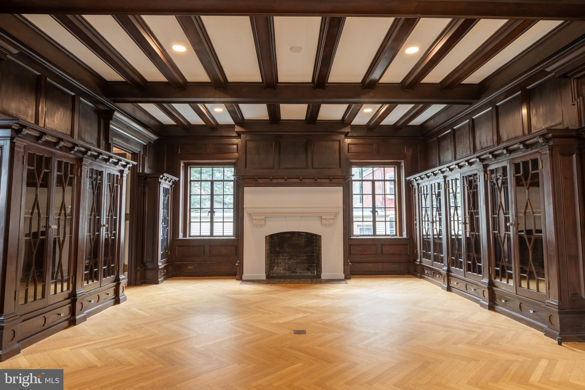 a view of an empty room with wooden floor and a fireplace