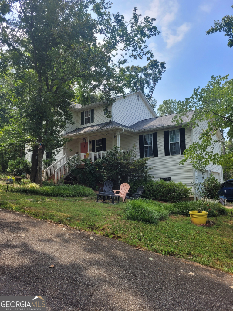 a front view of a house with a garden and tree