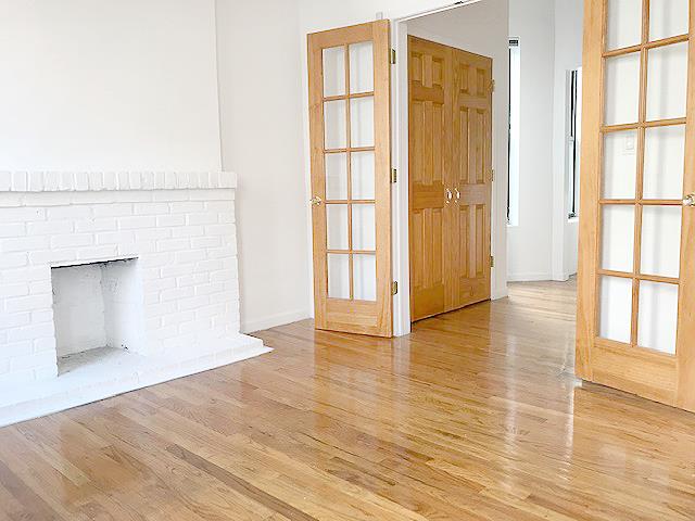 a view of an empty room with window and wooden floor