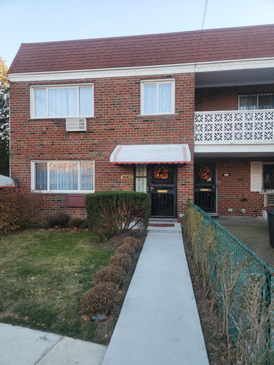 View of front of home featuring a balcony, a front lawn, and a wall mounted air conditioner