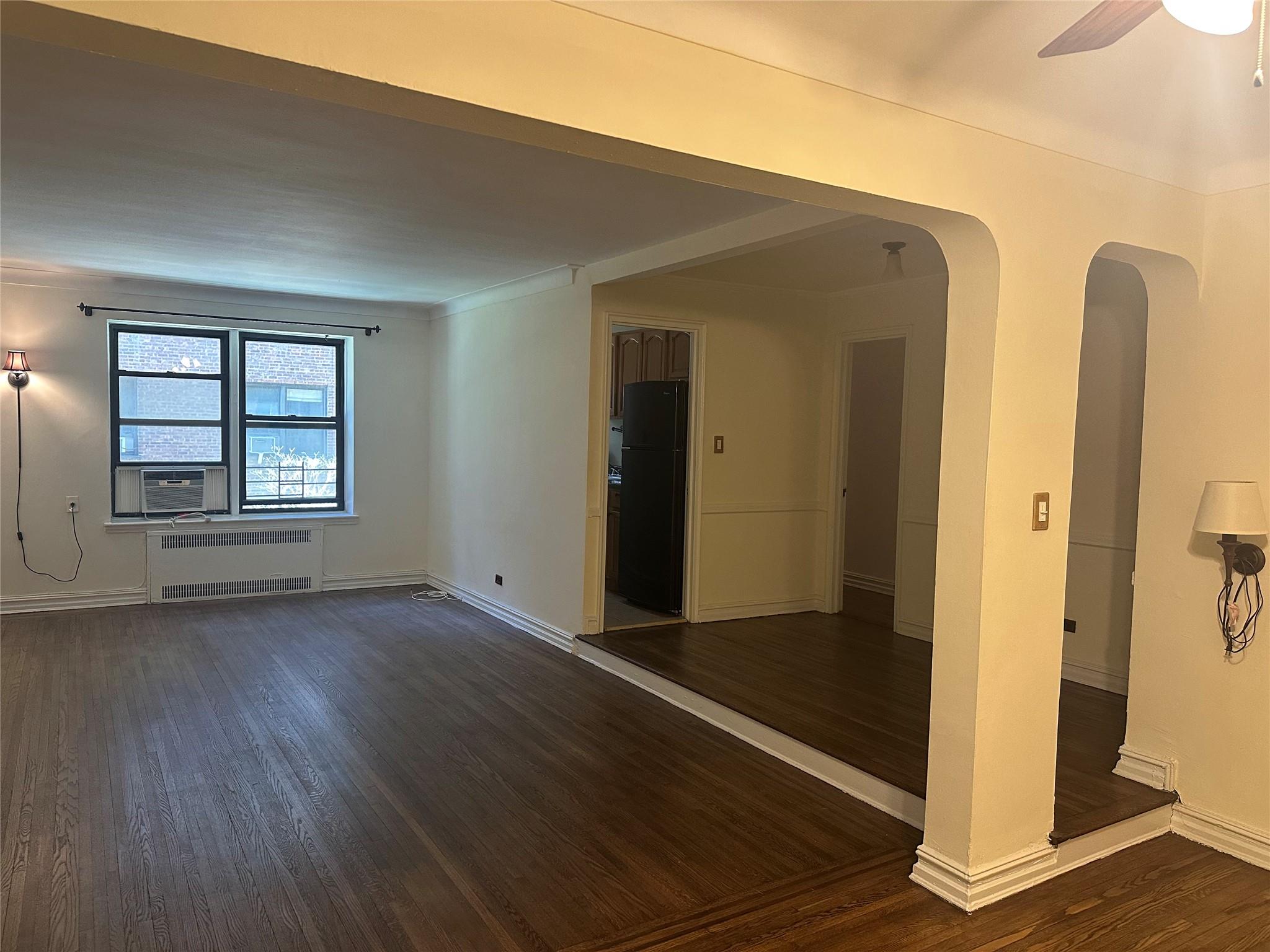 Unfurnished room with dark hardwood / wood-style flooring, radiator, cooling unit, and ceiling fan