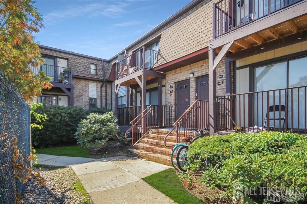 a view of a house with brick walls plants and large tree