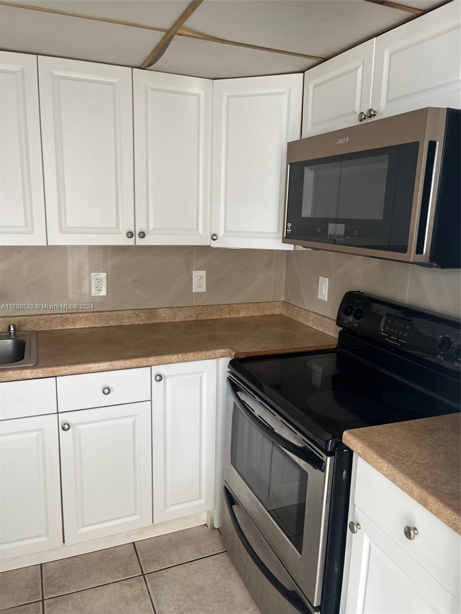 a kitchen with white cabinets and black appliances