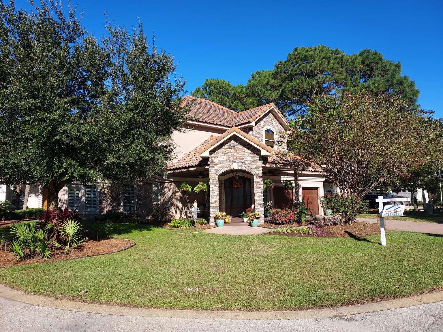 a front view of a house with garden and trees