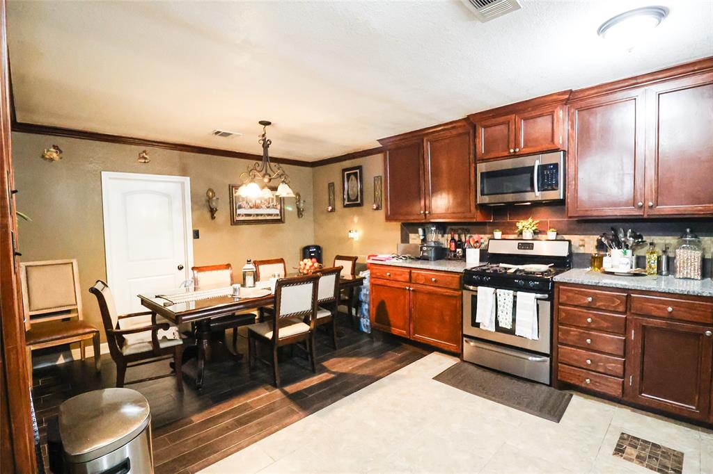 a kitchen with stainless steel appliances granite countertop a stove top oven a sink a dining table and chairs