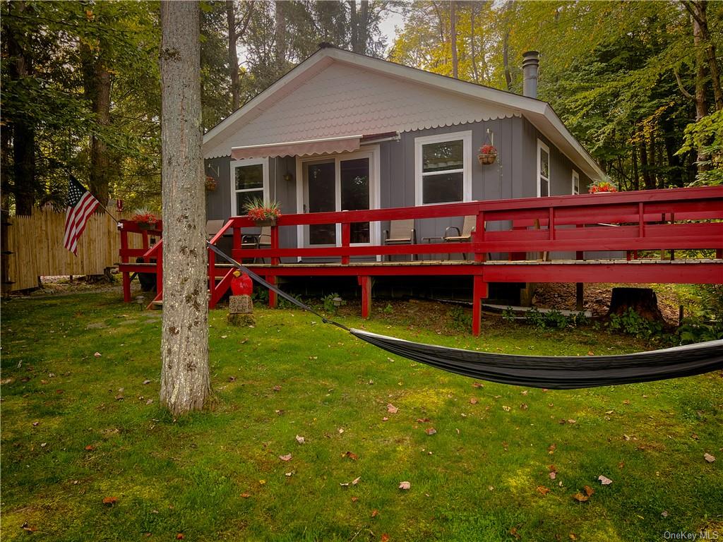 Rear view of house featuring a lawn and a deck