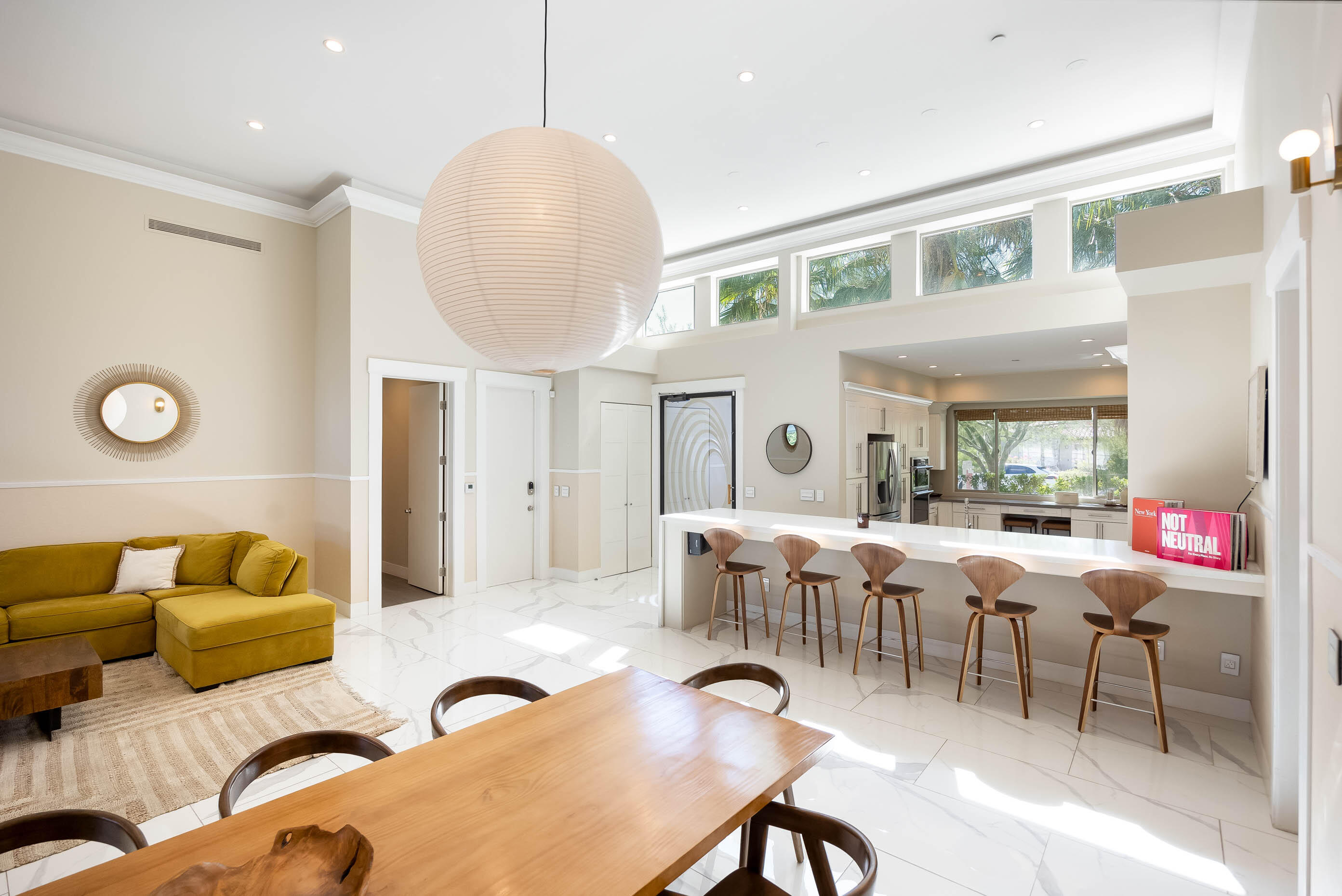 a living room with furniture kitchen view and a large window