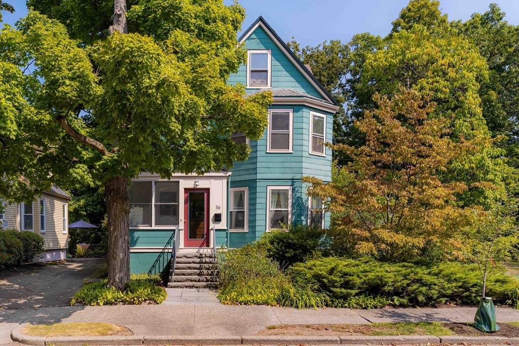 a front view of a house with a yard and potted plants