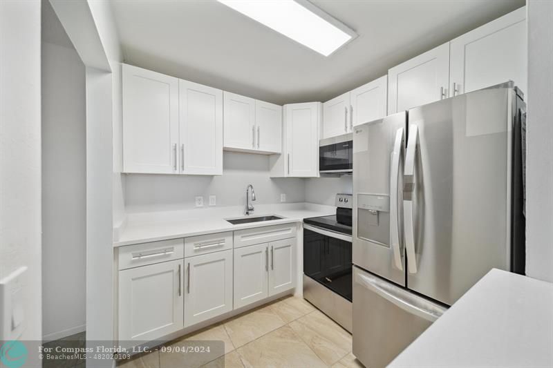 a kitchen with stainless steel appliances granite countertop a refrigerator sink and stove