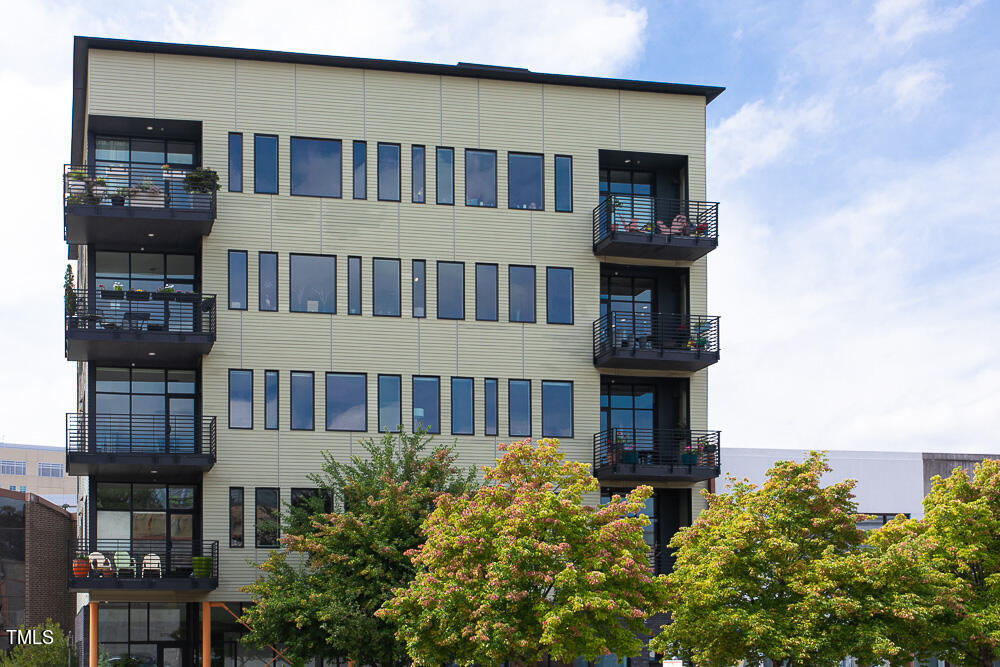 a front view of a building with balcony and residential houses