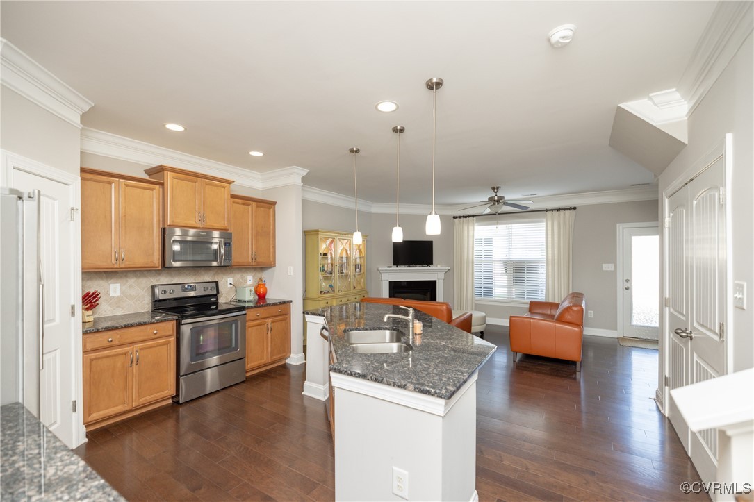 a kitchen with stainless steel appliances kitchen island granite countertop a stove top oven a sink dishwasher a dining table and chairs with wooden floor