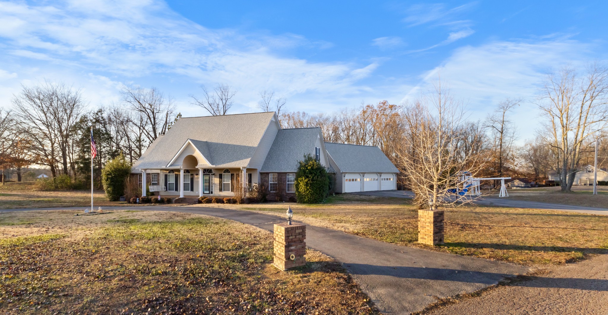 a front view of a house with a yard covered with snow and trees