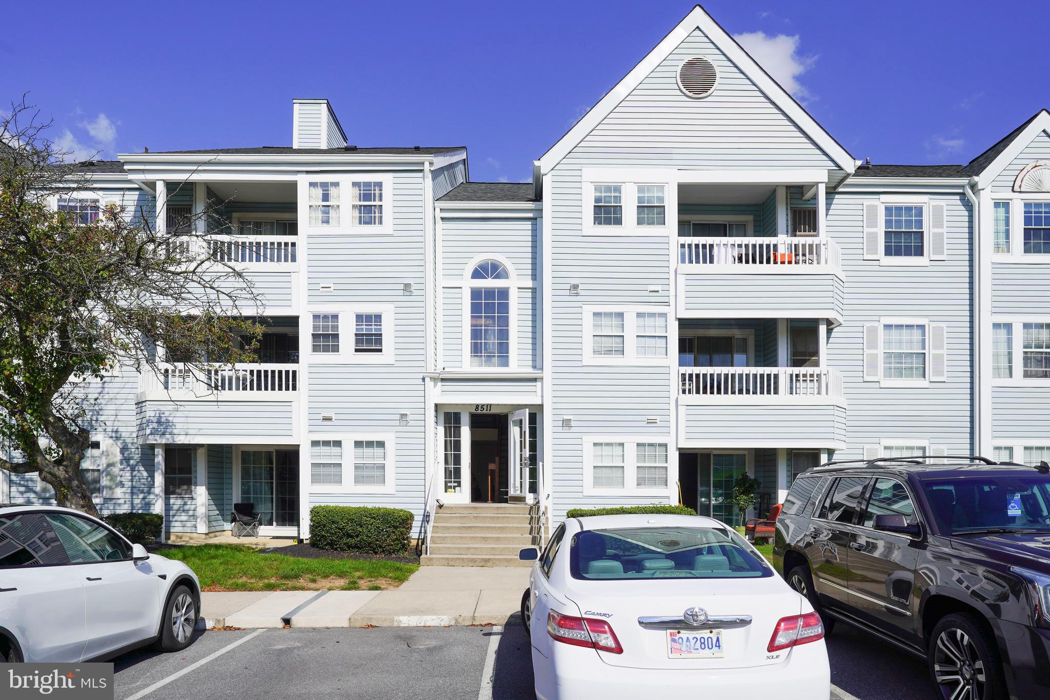 a front view of residential houses with cars parked on city street