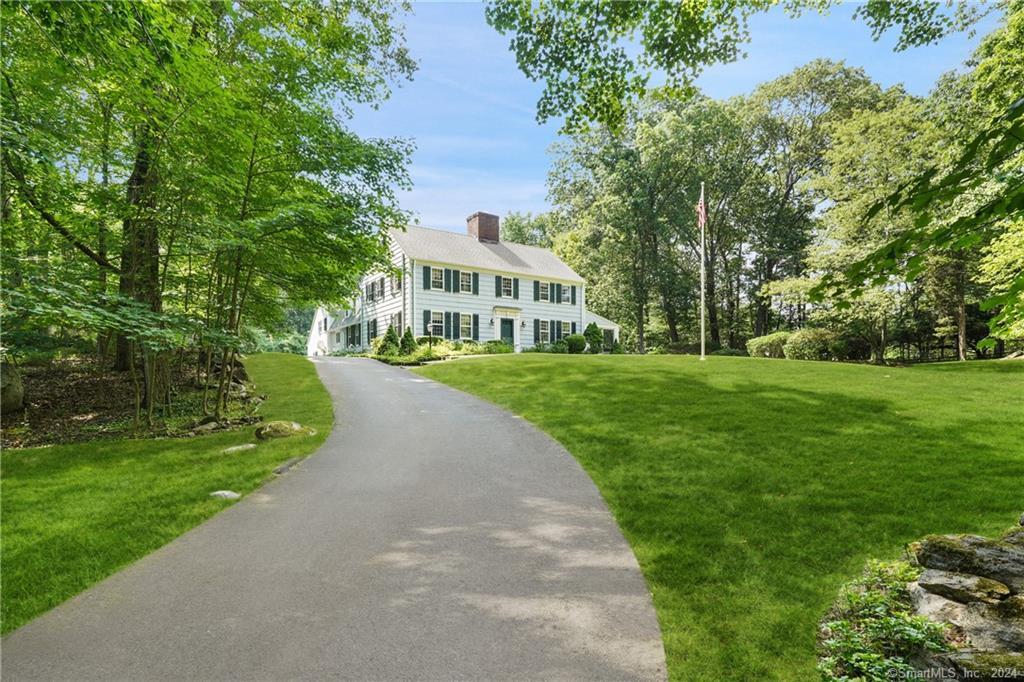 a view of a big house with a big yard and large trees