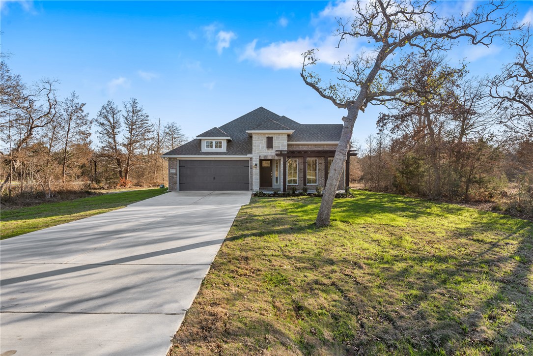 View of front of house with a front yard and a gar