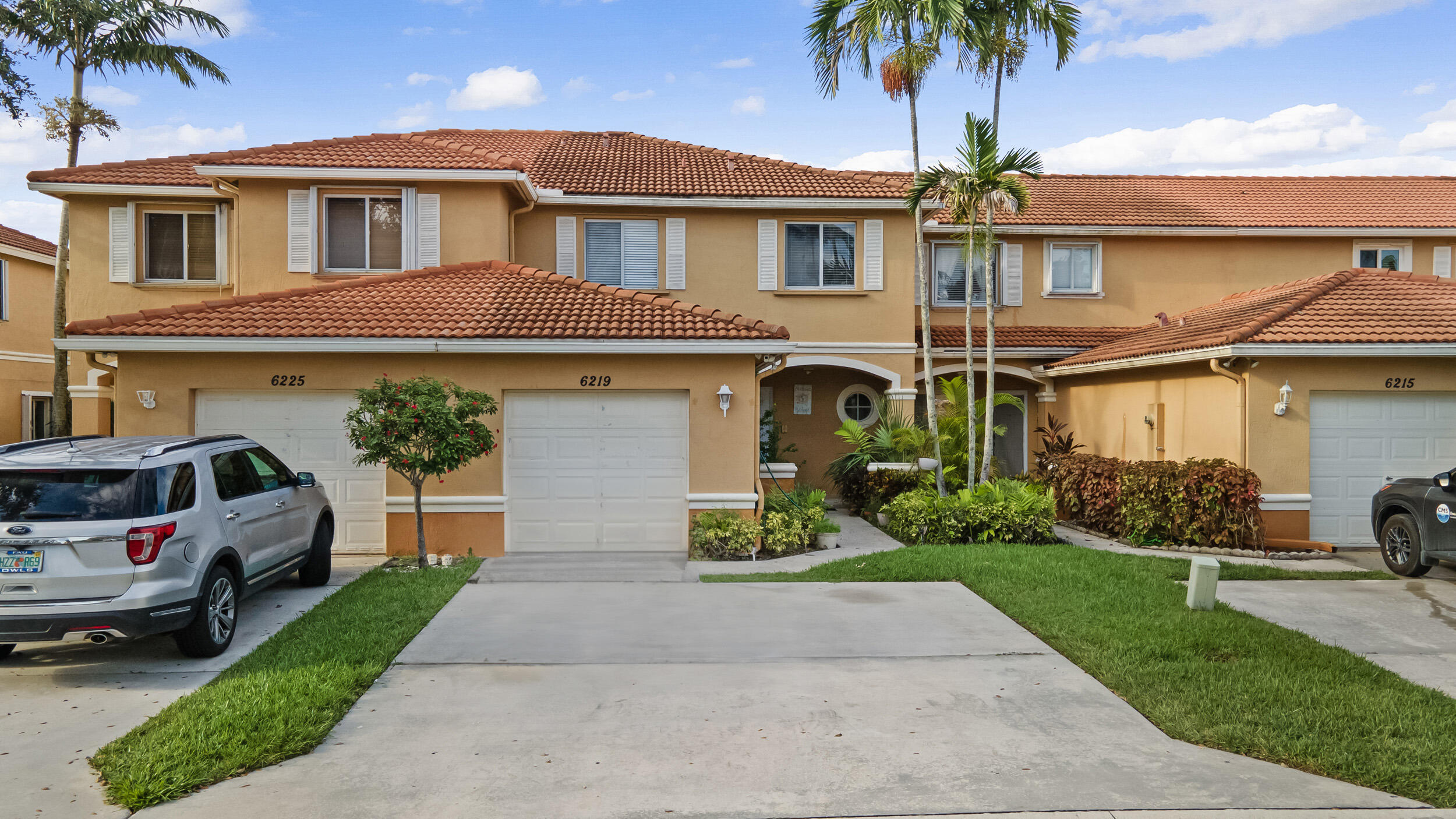 a front view of a house with a garden and palm trees