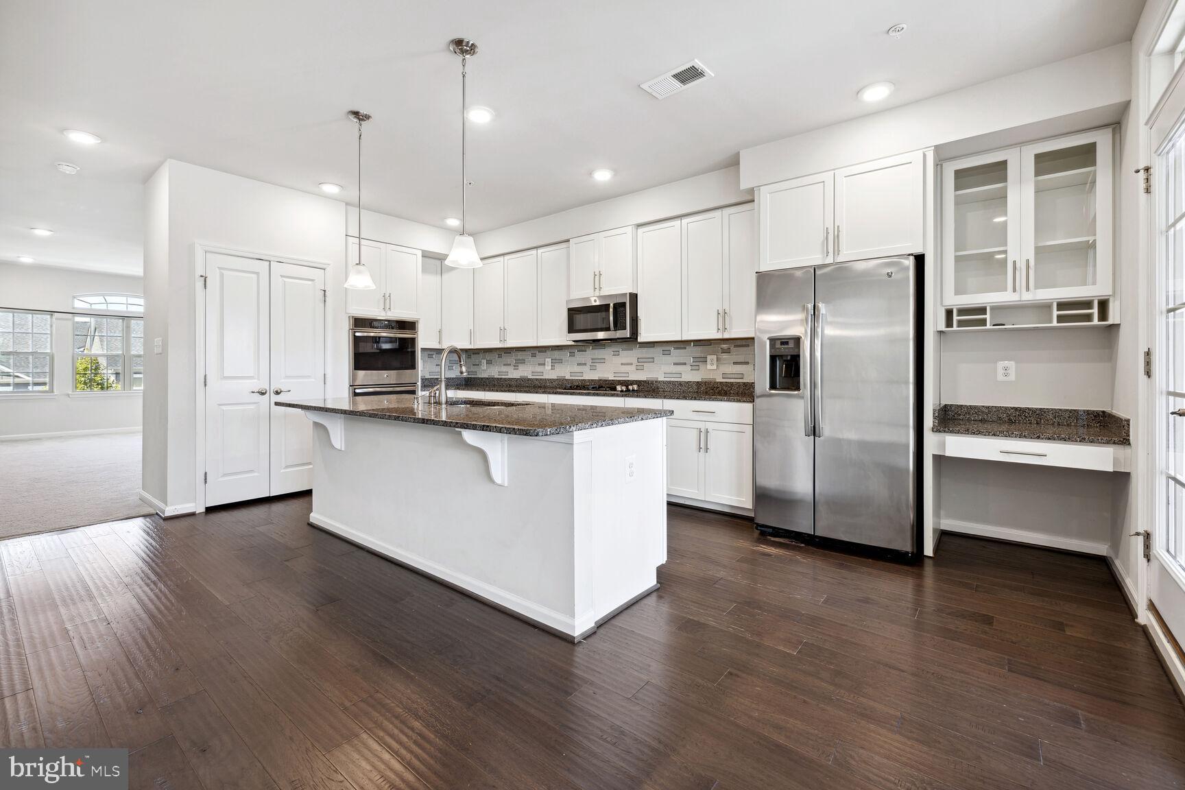 a kitchen with stainless steel appliances kitchen island granite countertop a refrigerator and a stove top oven