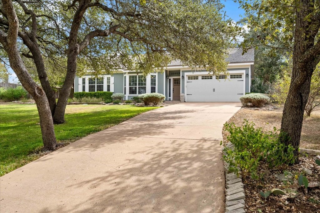 a front view of a house with a garden and trees