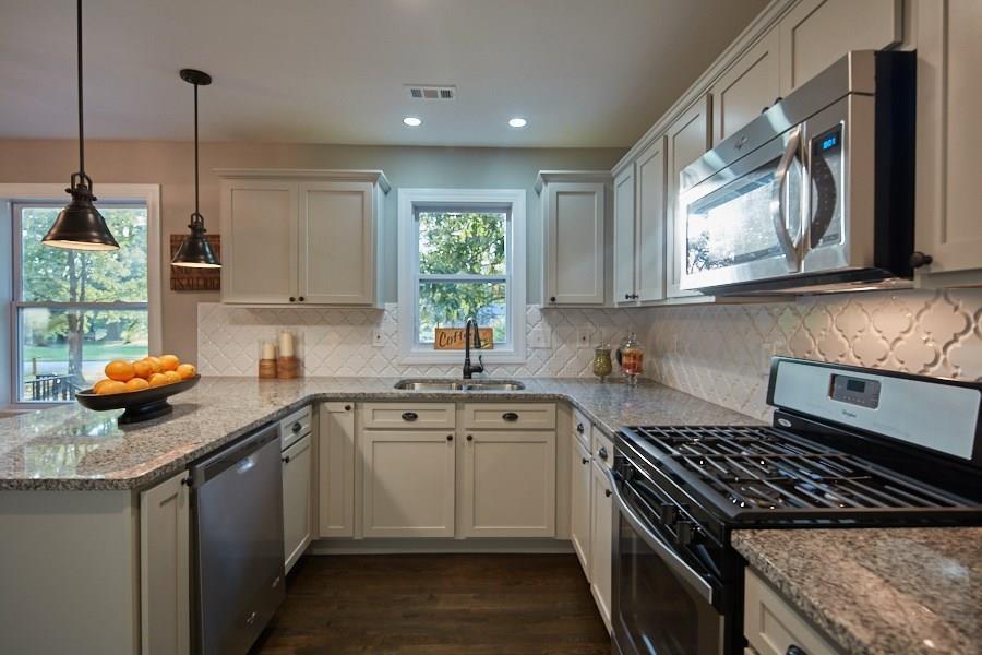 a kitchen with stainless steel appliances a stove a sink a stove a microwave a sink a window and cabinets