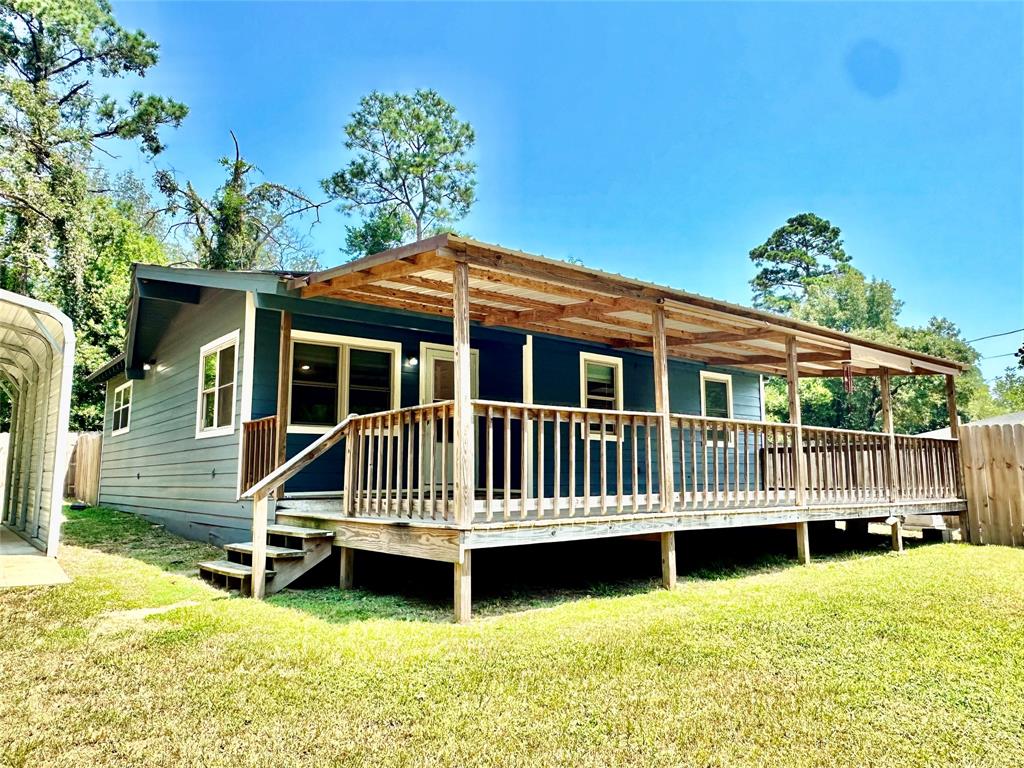 a view of a house with a wooden deck and a yard