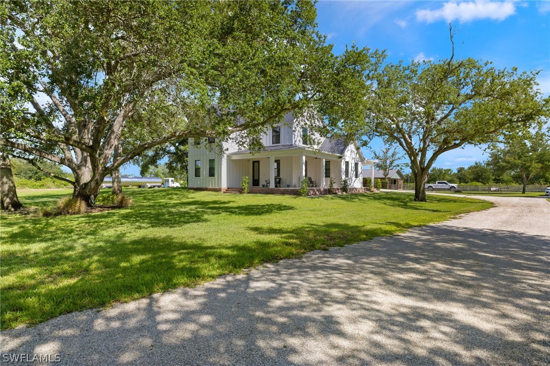 a view of a house with a big yard and large trees