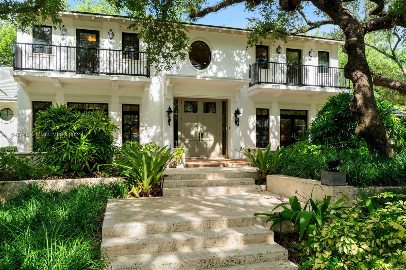 a view of a white house with a yard and potted plants