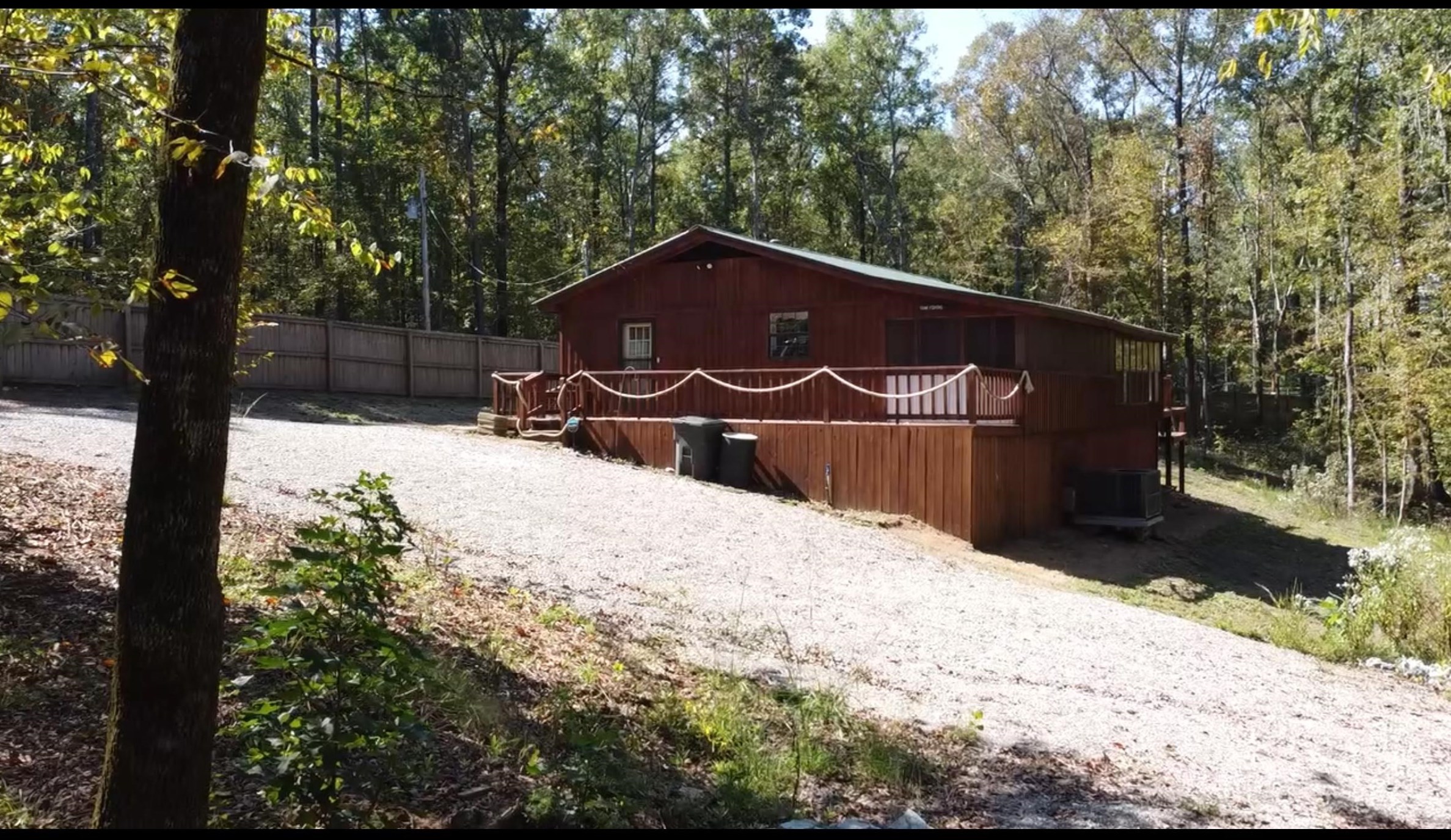 a backyard of a house with large trees and covered with wooden fence