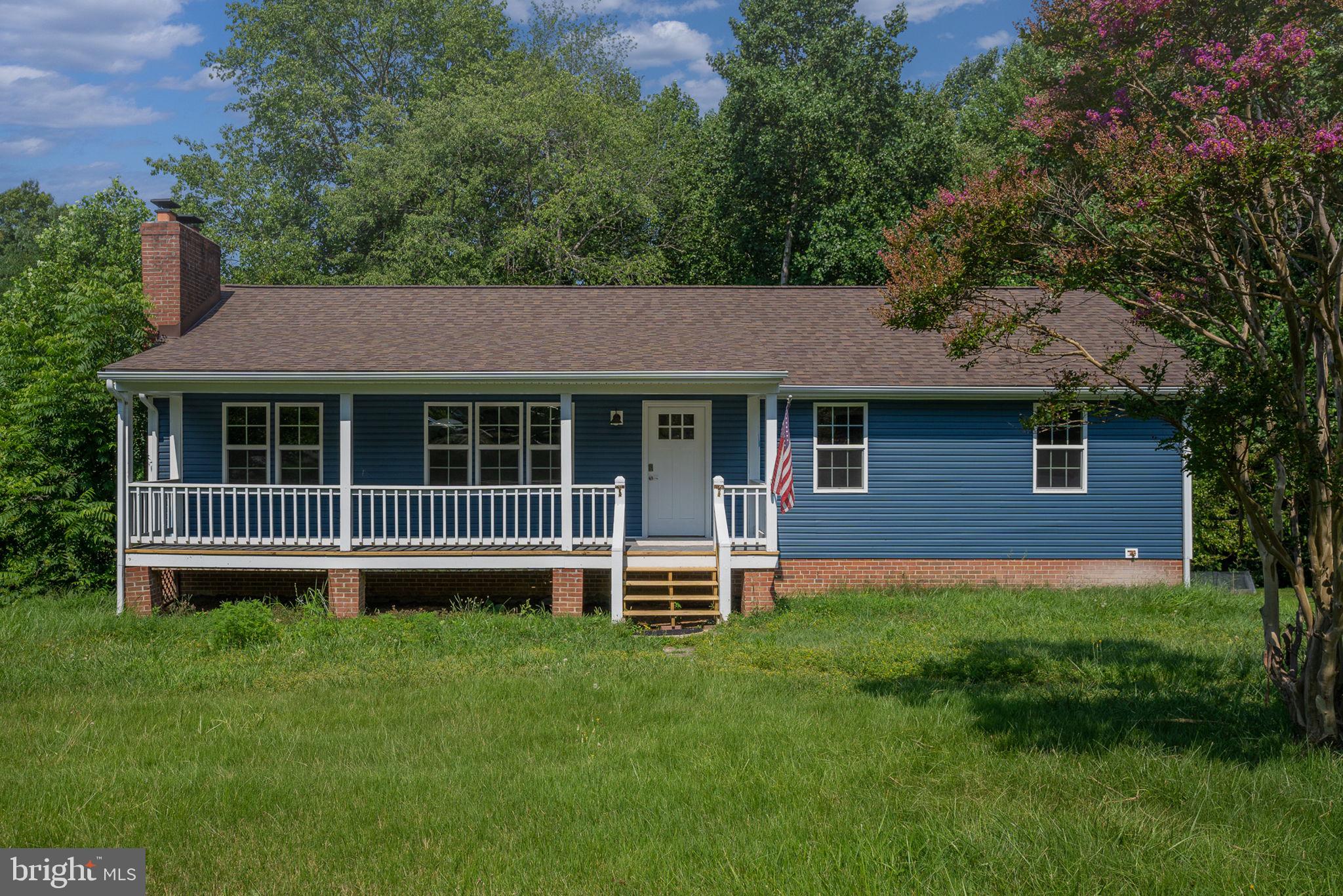 a view of a house with a yard and a large tree