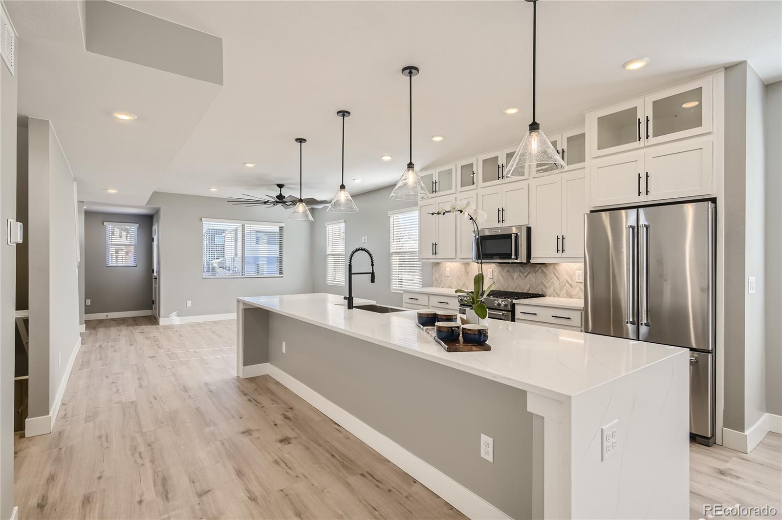 a view of a kitchen with stainless steel appliances kitchen island a refrigerator sink and wooden floor