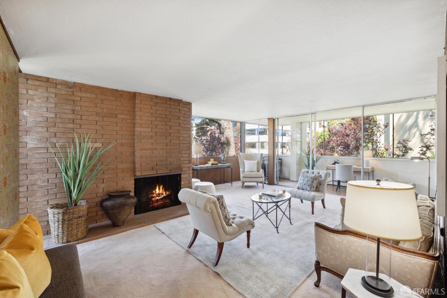 a living room with furniture a fireplace and a floor to ceiling window