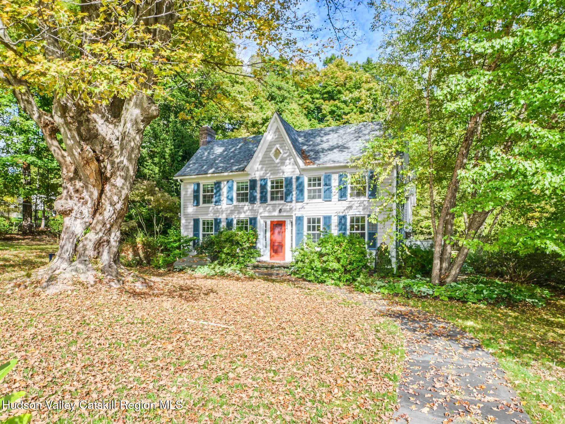 a front view of a house with a garden and trees