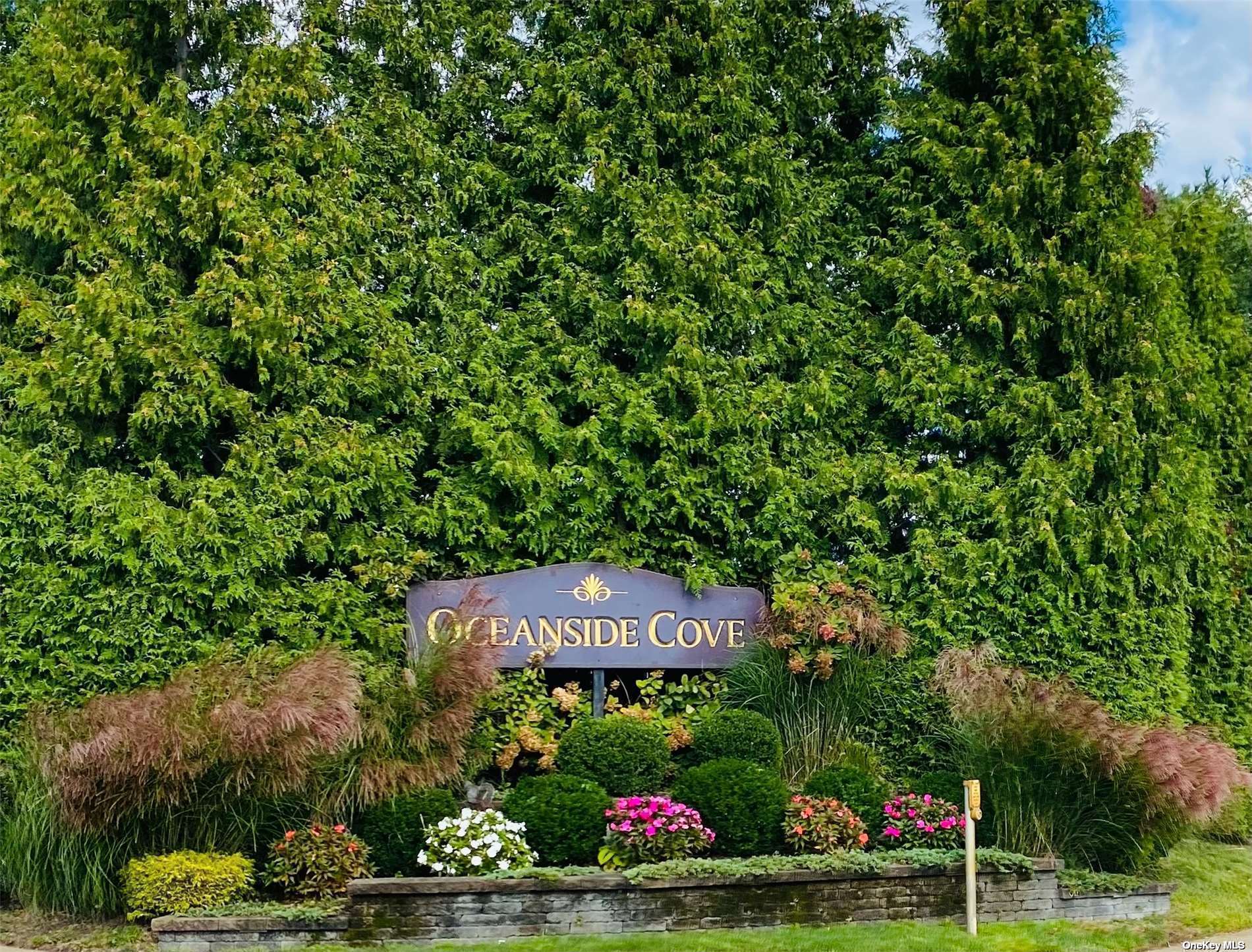 a sign that is sitting in front of a house with a tree