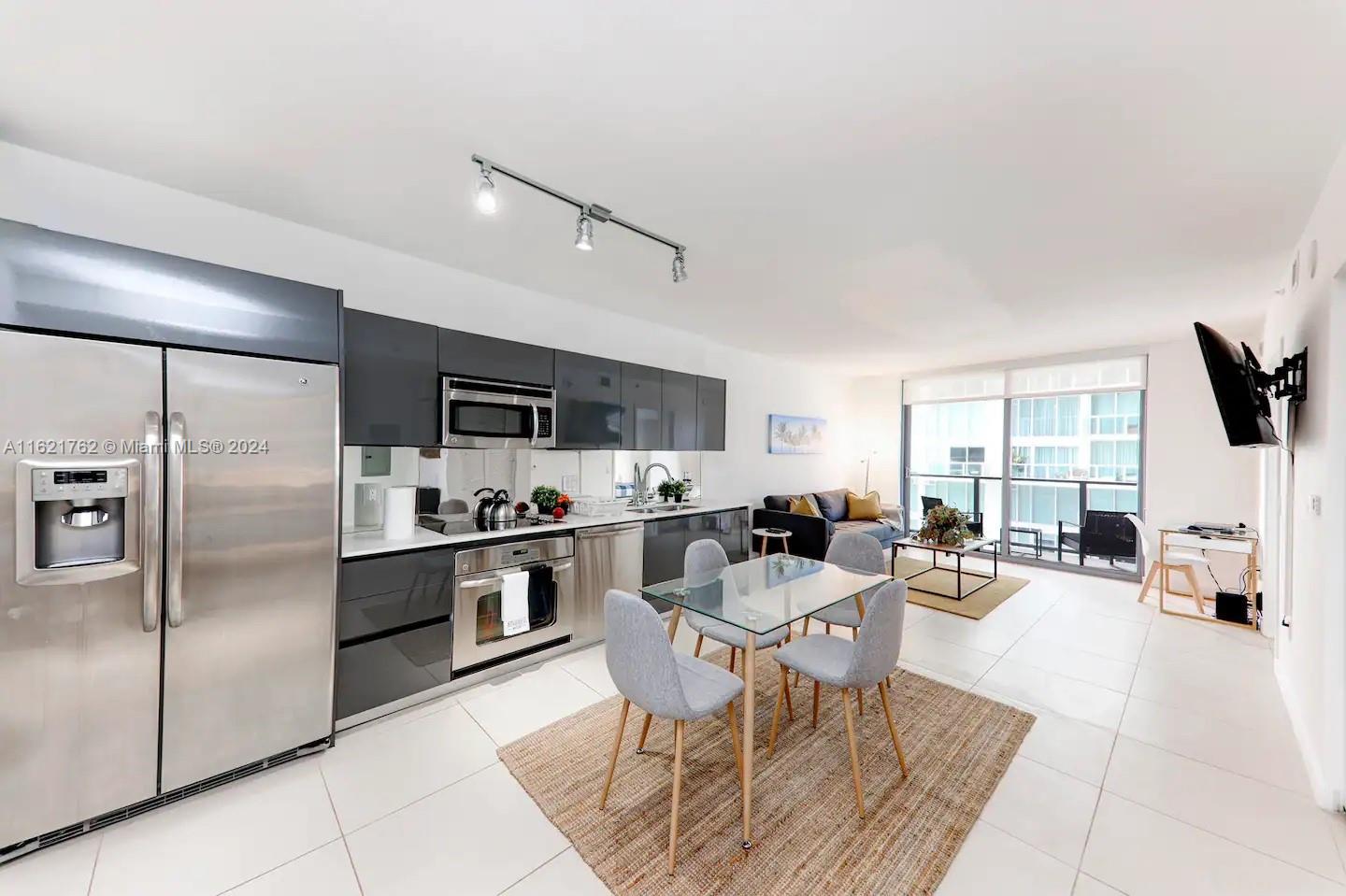 a living room with stainless steel appliances furniture a rug and a kitchen view