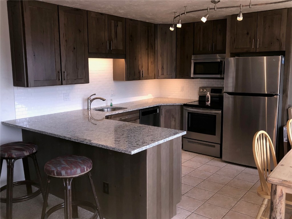 a kitchen with stainless steel appliances wooden cabinets a sink and a refrigerator