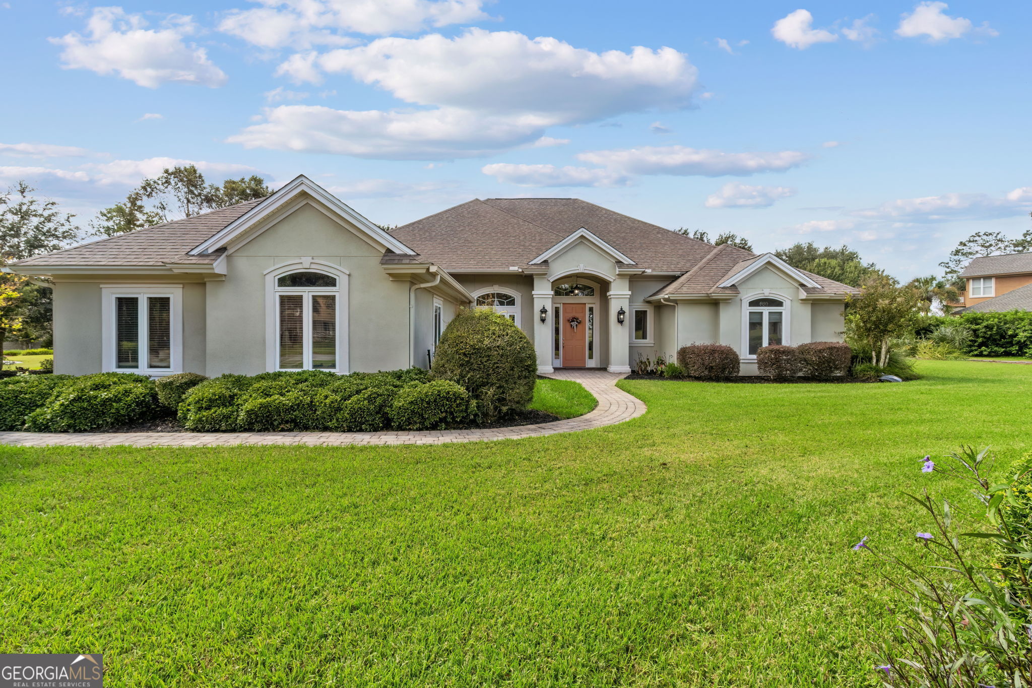 a front view of a house with a garden and yard