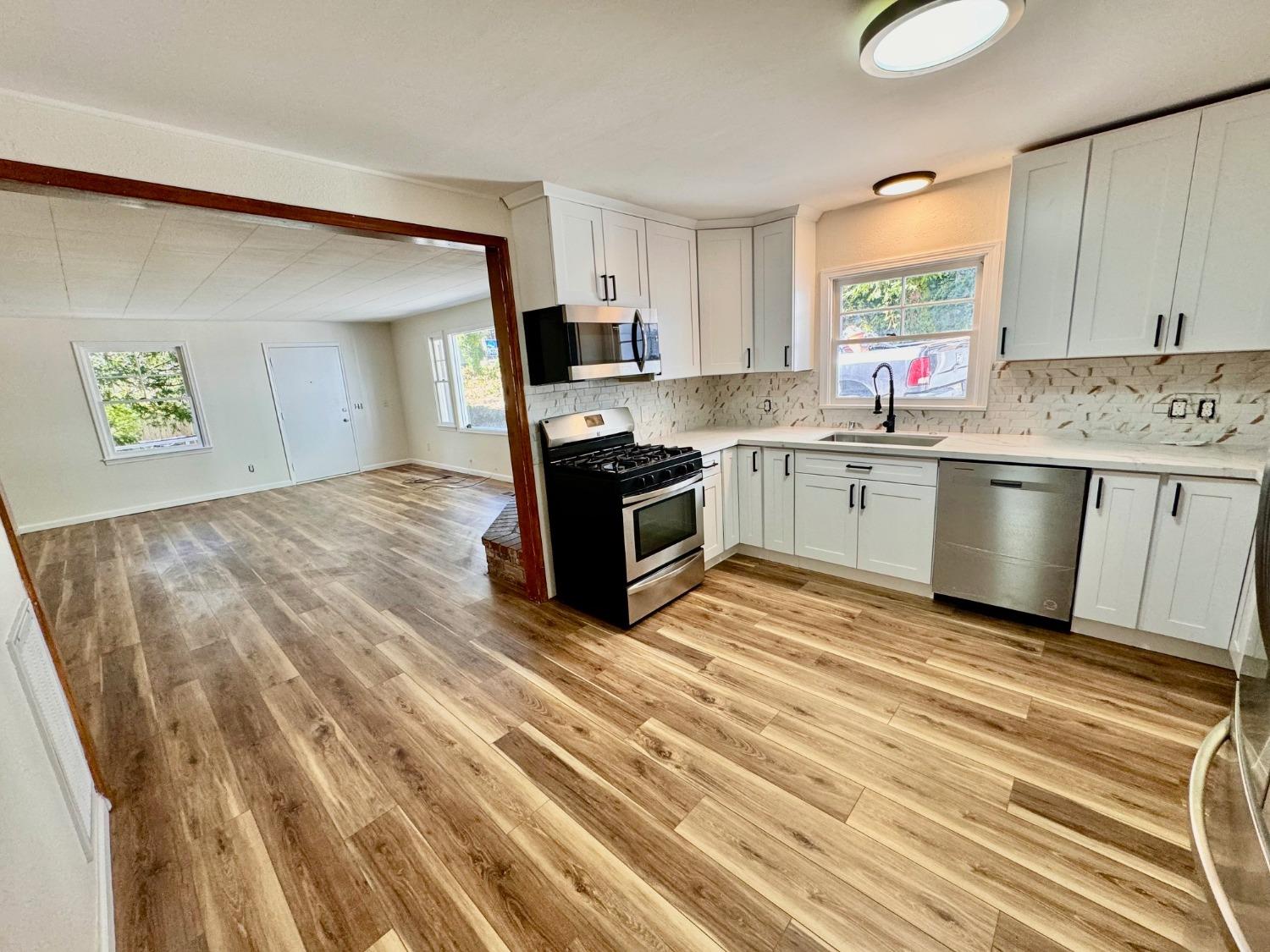 a kitchen with granite countertop a sink cabinets and stainless steel appliances