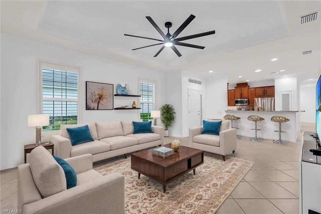 Living room featuring ornamental molding, ceiling fan, and light tile patterned floors