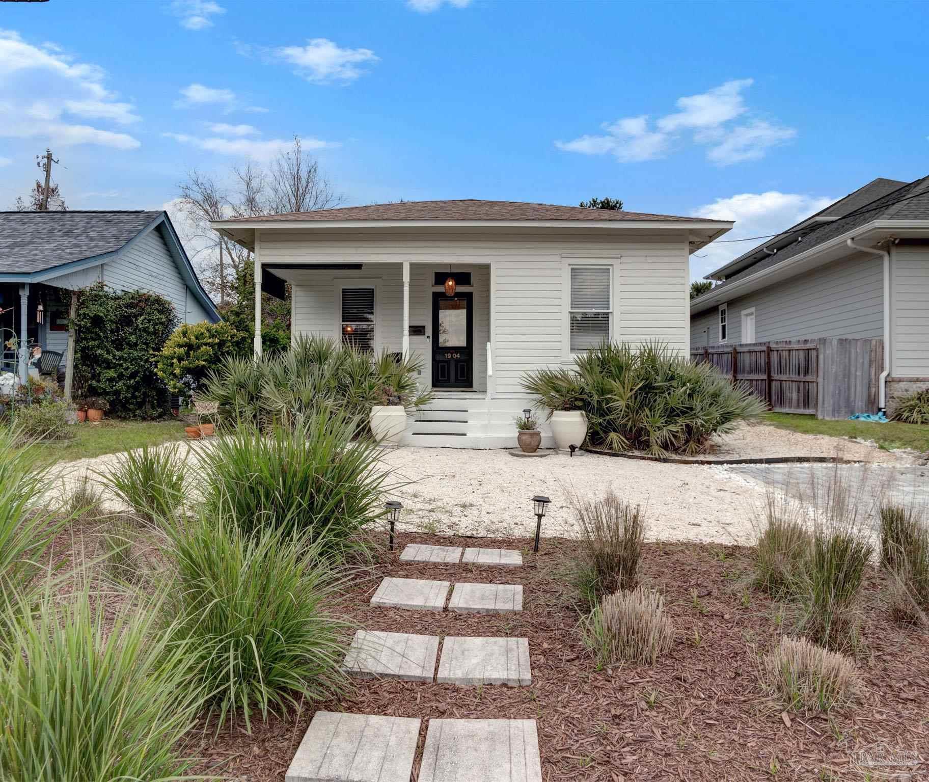 a front view of a house with a yard and potted plants