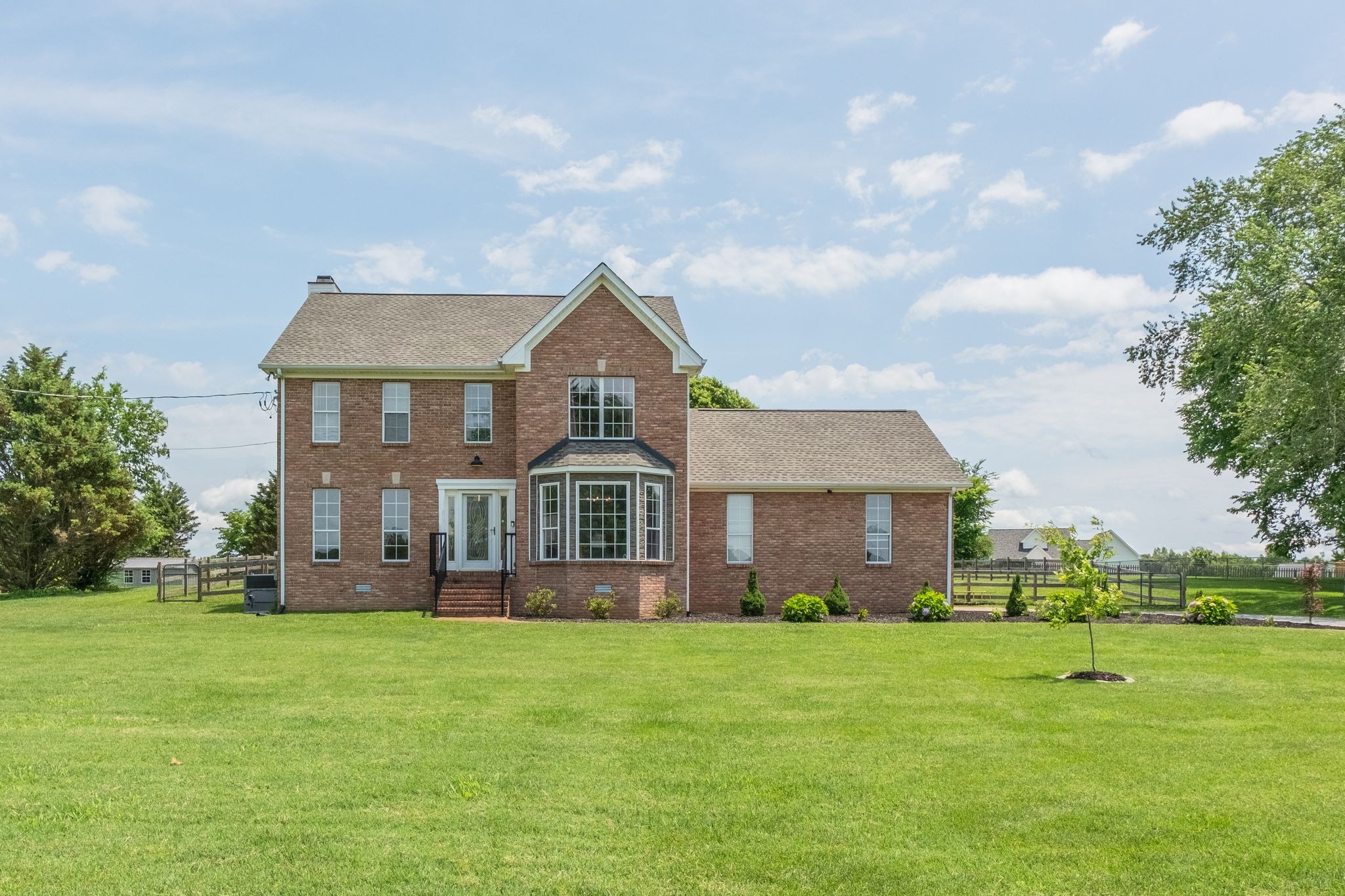 a front view of a house with a garden and trees