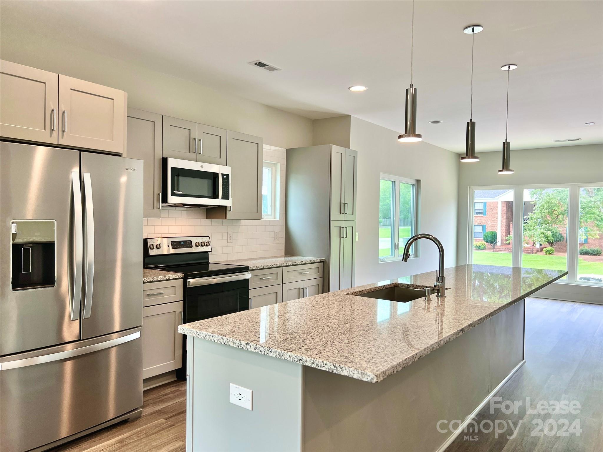 a kitchen with kitchen island granite countertop a sink a counter space stainless steel appliances and cabinets