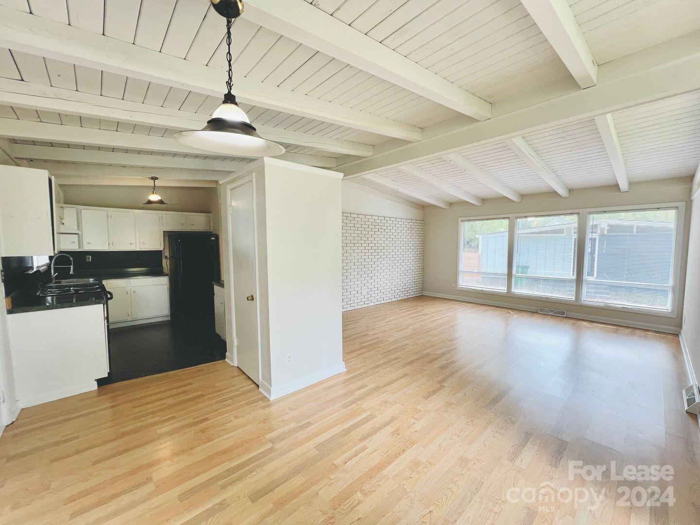 a view of an empty room with window and wooden floor