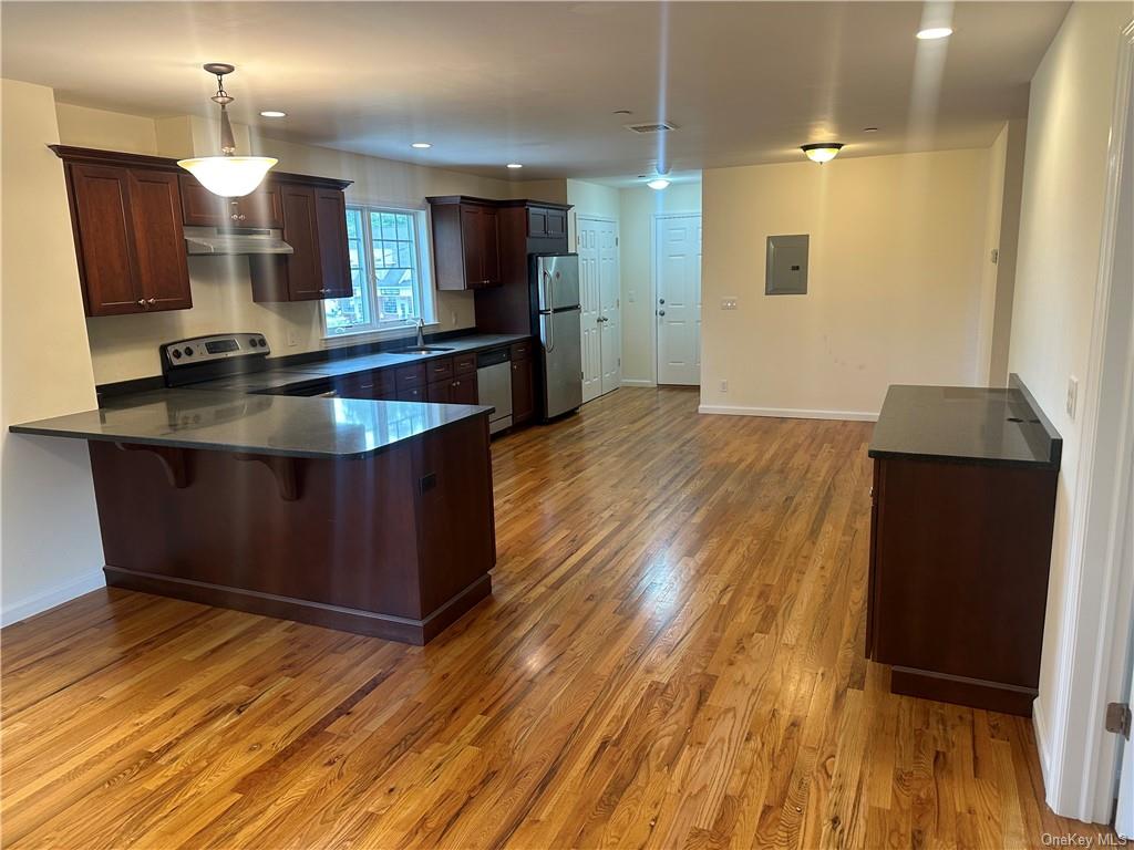 a kitchen with kitchen island granite countertop wooden floors and a sink