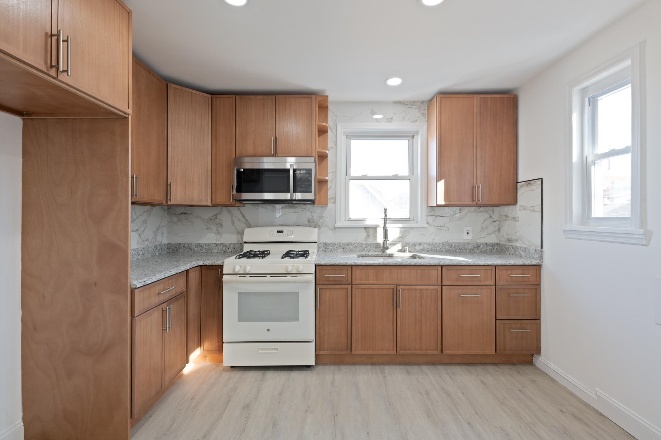 a kitchen with stainless steel appliances granite countertop a stove a sink dishwasher and a microwave oven with wooden floor