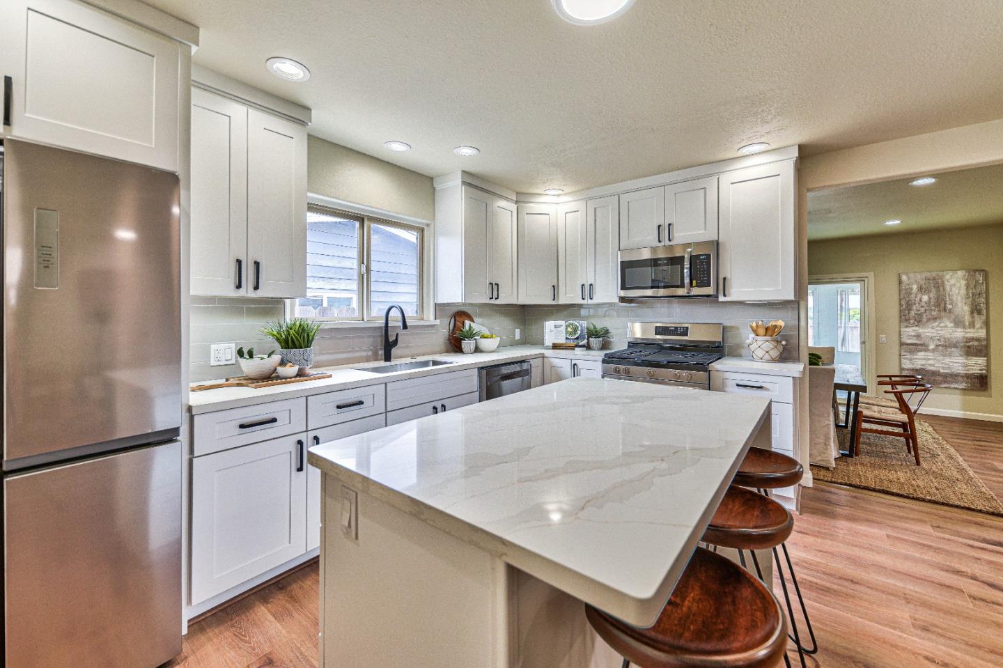 a kitchen with kitchen island a counter top space a sink stainless steel appliances and cabinets