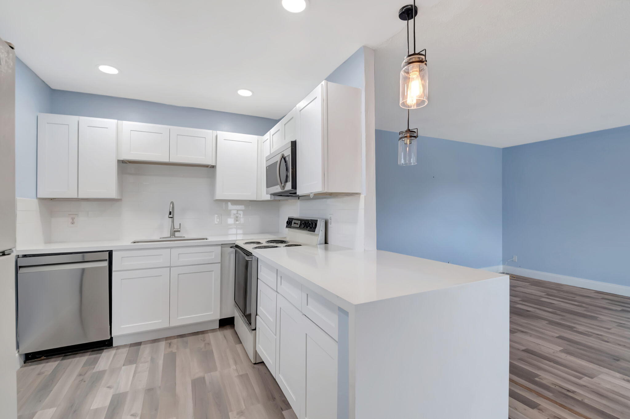 a kitchen with a sink a stove a refrigerator and white cabinets