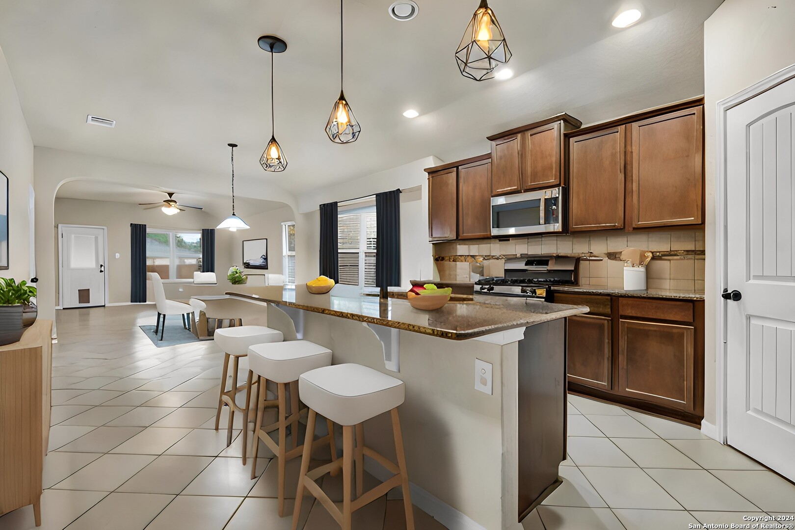 a kitchen with stainless steel appliances a stove center island a refrigerator and a view of living room