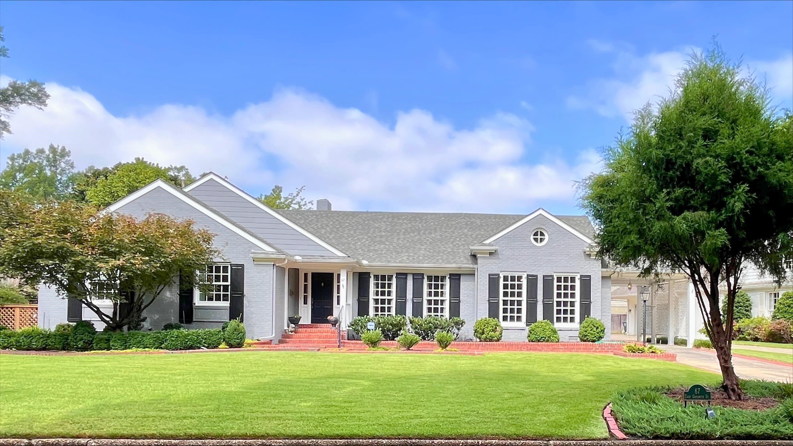 a front view of a house with garden and trees