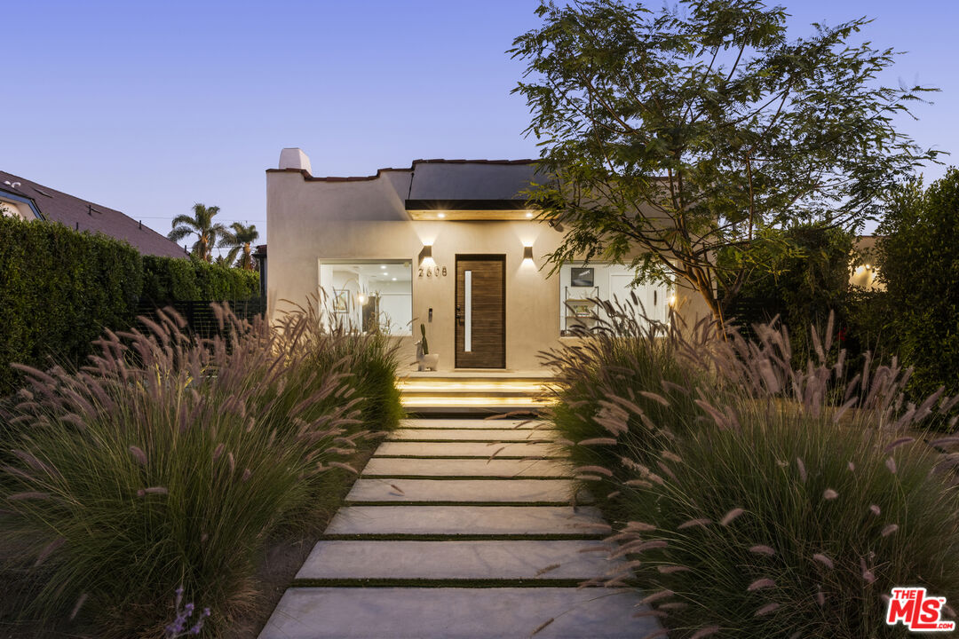 a view of a house with a small yard plants and large tree